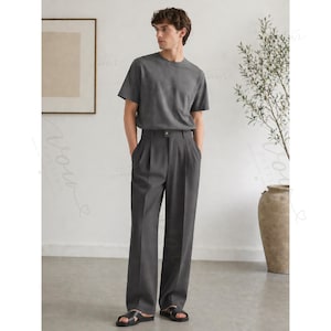 Op de afbeelding: Een antracietgrijs T-shirt met korte mouwen gecombineerd met een bijpassende antracietgrijze broek met hoge taille, plooien aan de voorzijde en rechte pijpen. De outfit wordt gecompleteerd door zwarte open sandalen aan de voeten.