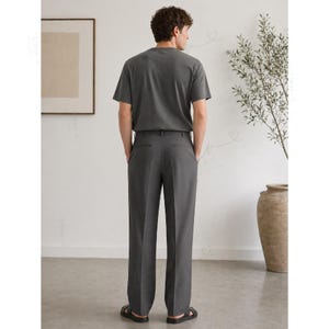 Op de afbeelding: Een antracietgrijs T-shirt met korte mouwen gecombineerd met een bijpassende antracietgrijze broek. De broek heeft een rechte snit met een strakke vouw in het midden van elke broekspijp, afgewerkt met zwarte sandalen.