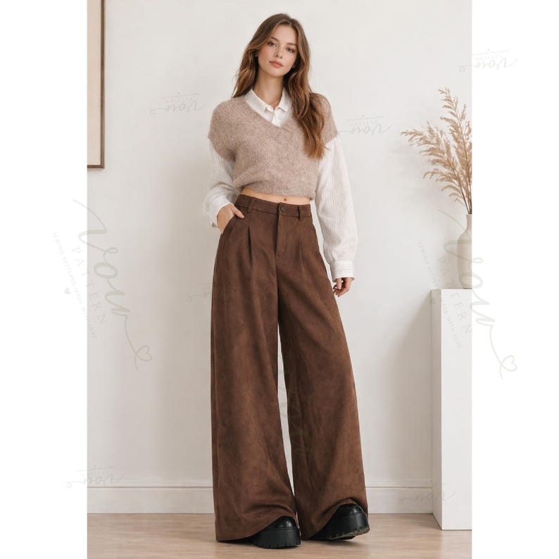May include: A beige V-neck knit sweater vest layered over a white long-sleeve button-down shirt, paired with high-waisted brown wide-leg trousers featuring a front button closure and black platform shoes.