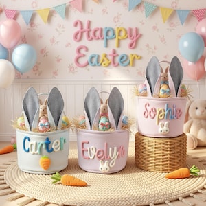 May include: Three Easter baskets with bunny ears, eggs, and stuffed bunnies. The baskets are personalized with names and sit on a woven mat. Balloons and a "Happy Easter" sign decorate the background. Carrots are placed around the baskets.