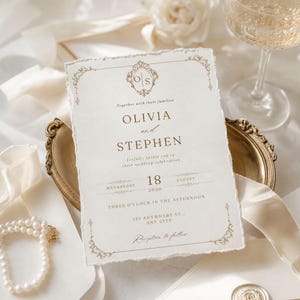 Op de afbeelding: Een rechthoekige trouwkaart met gescheurde randen, voorzien van goudkleurige tekst en sierlijke hoekversieringen. De tekst vermeldt Olivia en Stephen, 18 augustus 2030, om 15:00 uur, met een O S monogram aan de bovenzijde.