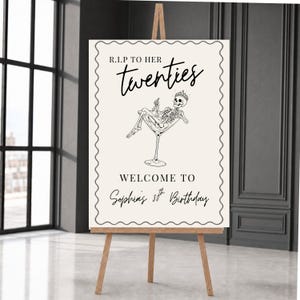 Op de afbeelding: Een rechthoekig verjaardags-welkomstbord met een golvende rand op een houten ezel. Het bord bevat de tekst R.I.P TO HER twenties, een zwart-witte illustratie van een skelet met een kroon in een martiniglas en WELCOME TO Sophia's 30th Birthday.