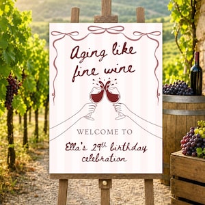 Puede incluir: Un caballete de madera muestra un letrero con el texto "Aging like fine wine". El letrero presenta dos manos brindando con copas de vino tinto. Da la bienvenida a los invitados a la celebración del 29 cumpleaños de Ella.