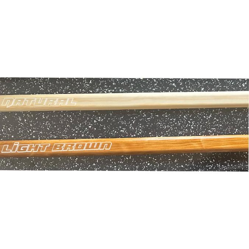 May include: Two wooden dowels, one natural and one light brown, are displayed against a speckled background. The text "NATURAL" is printed on the top dowel, and "LIGHT BROWN" is printed on the bottom dowel.