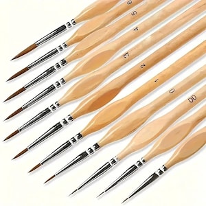 May include: A set of ten fine-tipped paint brushes. Each brush has a light-colored wooden handle with a rounded, ergonomic design. The bristles are brown, and the ferrules are silver-colored. Numbers 00 through 6 are printed on the handles.