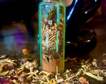 May include: A small, clear glass bottle filled with dried herbs and crystals, sealed with a cork and green wax. The bottle is surrounded by loose dried flowers and herbs, creating a mystical aesthetic. The background is blurred, with a dark, glossy object.