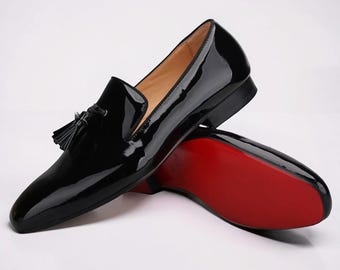Zapatos de vestir tipo mocasín para hombre, de piel de becerro negra con suela roja y borlas.