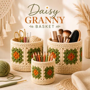 May include: Three handmade crochet baskets in varying sizes. The baskets are beige with green and orange floral patterns. The largest basket holds makeup brushes, the medium basket holds pencils, and the smallest basket holds scissors and crochet hooks. The text "Daisy Granny Basket" is at the top.