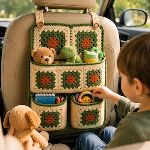 May include: A crochet car seat organiser featuring a granny square pattern in cream, forest green, and burnt orange. It has one large top pocket and two smaller bottom pockets, secured to the headrest with two straps and wooden buttons.