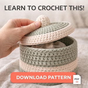 Puede incluir: Caja de almacenamiento tejida a ganchillo en verde y crema. El texto "LEARN TO CROCHET THIS!" está en la parte superior y "DOWNLOAD PATTERN" en la inferior. La tapa está ligeramente abierta, mostrando el interior. Icono PDF.