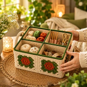 May include: A beige crochet yarn organiser with green trim and handles. The organiser is divided into six compartments, filled with yarn balls, crochet hooks, scissors, and a floral pin cushion. The front features a red and green floral design.