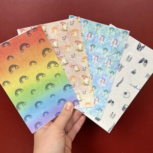 May include: Five patterned sheets with various designs, including rainbows, gnomes with mushrooms, fairies, and anatomical drawings. The rainbow sheet has a gradient of colors, while the others feature repeating patterns on a textured surface.