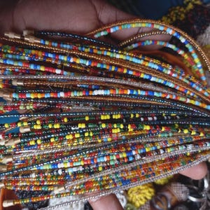 May include: A collection of colorful beaded strands, each with a unique pattern of small beads in various colors. The beads are strung together, creating a vibrant and textured appearance. The strands are held together, showcasing the variety of designs.