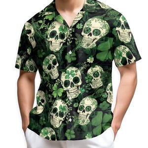May include: Short-sleeved button-down shirt with a repeating pattern of cream-colored skulls and green shamrocks on a black background. The shirt has a classic collar and is made of a lightweight fabric.