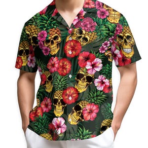 Può includere: Camicia a maniche corte con sfondo verde scuro. La camicia presenta un motivo ripetuto di teschi dorati, ananas e fiori tropicali rossi, rosa e bianchi. La camicia ha un colletto classico.