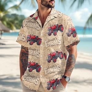 Puede incluir: Camisa beige de manga corta con un estampado repetido de tractores rojos y el texto "Smith's FARMS". La camisa tiene un corte holgado. El fondo incluye una escena de playa.