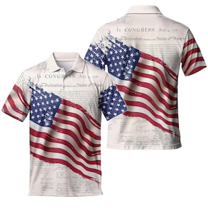 May include: A white polo shirt featuring a distressed American flag design with red and white stripes and blue stars. The shirt includes the text "IN CONGRESS. JULY 4. 1776." and excerpts from the Declaration of Independence.