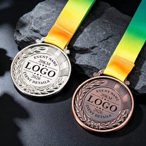 May include: Two circular medals, one silver and one bronze, featuring a laurel wreath border and center text reading EVENT NAME, 20KM, LOGO, 2026, and EVENT DETAILS. Each medal is attached to a yellow and green gradient ribbon with a textured finish.