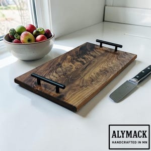 May include: A white ceramic mug with a black handle and the text "But First, Coffee" in a black, bold font. The mug is on a white surface. The mug is approximately 4 inches tall.