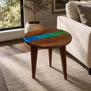 May include: A round side table featuring a dark brown wooden top with a central inlay of vibrant blue and green resin. The table is supported by three tapered wooden legs that match the tone and grain of the circular tabletop surface.