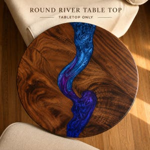 May include: A round river table top featuring a natural dark wood grain surface bisected by a swirling, metallic blue and purple resin inlay. The text ROUND RIVER TABLE TOP TABLETOP ONLY is printed in black above the circular wooden piece.