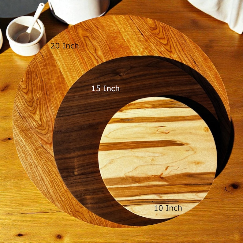 K&ouml;nnte beinhalten: Drei runde Holzschneidebretter in verschiedenen Gr&ouml;&szlig;en. Das gr&ouml;&szlig;te hat einen Durchmesser von 20 Zoll (50,8 cm), das mittlere 15 Zoll (38,1 cm) und das kleinste 10 Zoll (25,4 cm). Die Holzmaserung und die Farben variieren, wobei das gr&ouml;&szlig;te Brett hellbraun ist.