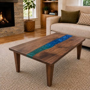 May include: A rectangular coffee table constructed from dark brown walnut wood featuring a central river design made of translucent blue and teal epoxy resin. The table is supported by four straight, tapered wooden legs in a matching finish.