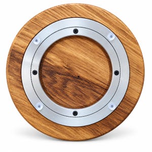 May include: A circular wooden lazy susan featuring a natural brown wood grain finish. The center contains a silver-toned metal rotating ring mechanism secured with four black screws and four small, clear, circular suction cup feet attached.