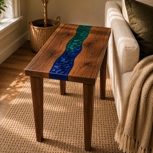 May include: A rectangular side table constructed from dark brown wood featuring a central, wavy inlay of translucent resin that transitions from a vibrant emerald green at the top to a deep royal blue at the bottom, supported by four straight legs.