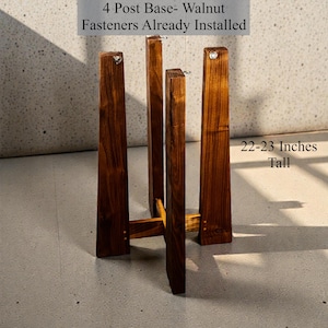 Może przedstawiać: Czteroramienna podstawa z orzecha włoskiego z zainstalowanymi mocowaniami. Drewniany stojak ma 56-58 cm wysokości. Tekst na zdjęciu brzmi: "4 Post Base- Walnut Fasteners Already Installed" i "22-23 Inches Tall".
