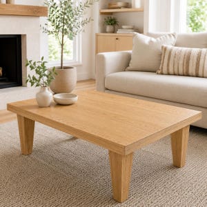 May include: A rectangular coffee table crafted from light-toned wood with a visible grain pattern, featuring four sturdy, slightly tapered legs. The table surface is smooth and flat, providing a clean, functional area for placement in a living space.