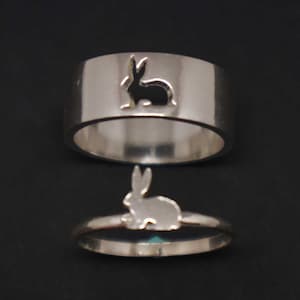 Puede incluir: Dos anillos de plata con un diseño de silueta de conejo. El anillo superior tiene un recorte de un conejo, mientras que el anillo inferior tiene un diseño de conejo sólido.