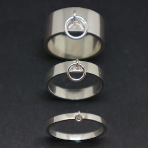 May include: Three silver rings with a small circle attached to the top of each ring. The rings are stacked on top of each other, with the largest ring on the bottom and the smallest ring on the top.
