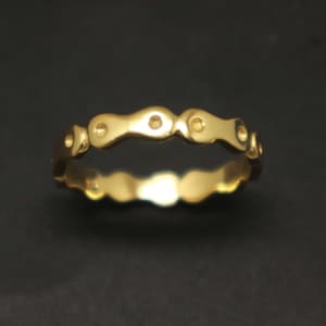 Puede incluir: Un anillo de banda de oro con un diseño ondulado y pequeños acentos redondos.