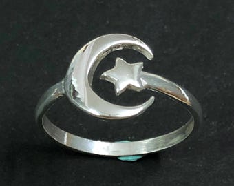 Puede incluir: Un anillo de plata con un diseño de luna creciente y estrella.