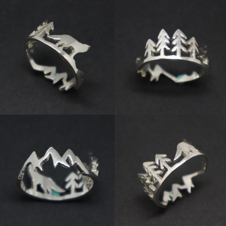 May include: Four silver rings with different nature-inspired designs. One ring features a wolf silhouette, another has a mountain range, and two rings have a silhouette of a group of trees.