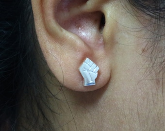 May include: A pair of silver earrings featuring a raised fist design.