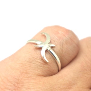 May include: A silver ring with a stylized design of two crescent moons intertwined.