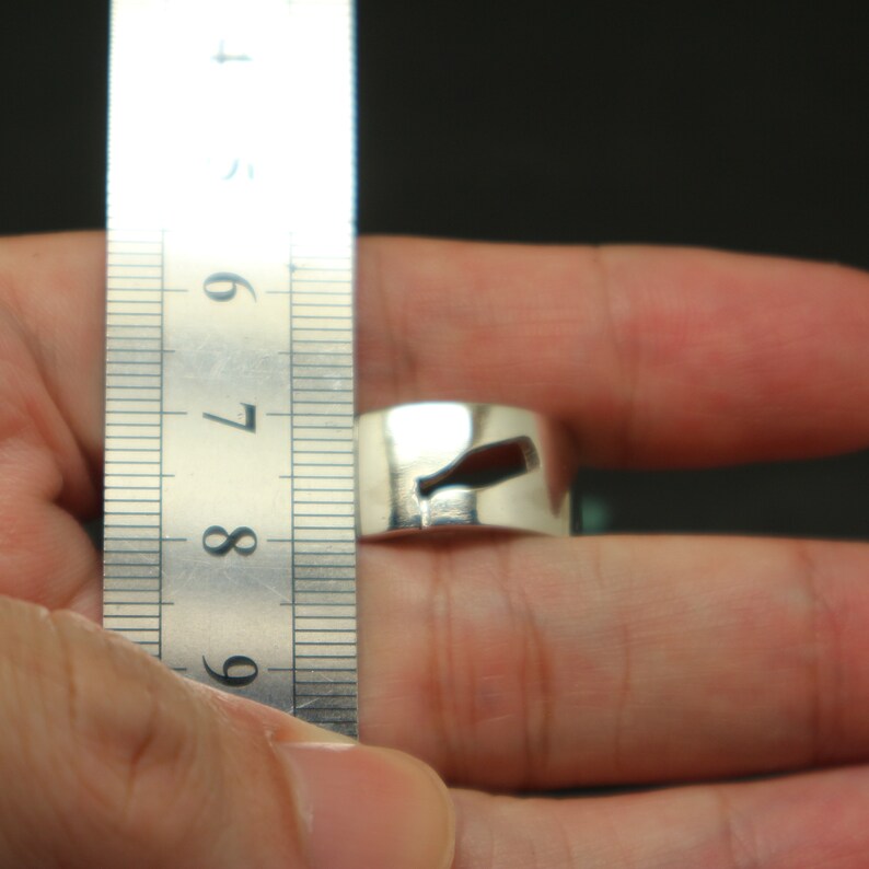 May include: A silver ring with a cut-out design, measured against a ruler. The ring is approximately 8.5 inches in diameter.