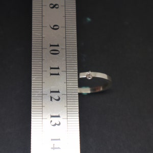 May include: A silver metal ring with a small loop attached to the top. The ring is measured against a ruler, showing it is approximately 11.5 inches in diameter.