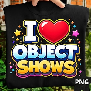 May include: Black sweatshirt with the text "I ❤️ OBJECT SHOWS" in a colorful, cartoonish design. The design includes a red heart, stars, and the letters in white, blue, and yellow. The sweatshirt is held up by a hand.