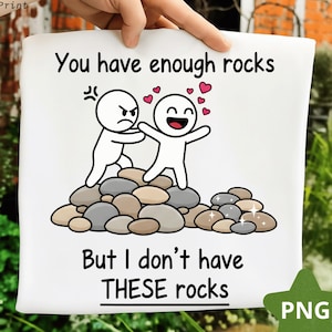 Może przedstawiać: Biała kwadratowa tkanina z napisem "You have enough rocks But I don't have THESE rocks" i kreskówkową ilustracją dwóch ludzików na stosie kamieni. Jedna postać jest zła, druga jest szczęśliwa.
