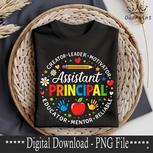 May include: Black t-shirt featuring a design for an Assistant Principal. The design includes the words "Assistant Principal" in bright colours, surrounded by words like "Creator," "Leader," and "Educator," along with a pencil, apple, and handprints.