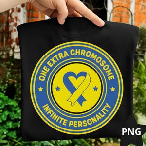 May include: Black sweatshirt with a circular design. The design features the text "ONE EXTRA CHROMOSOME INFINITE PERSONALITY", a blue ribbon in a heart shape on a yellow background, and blue stars.