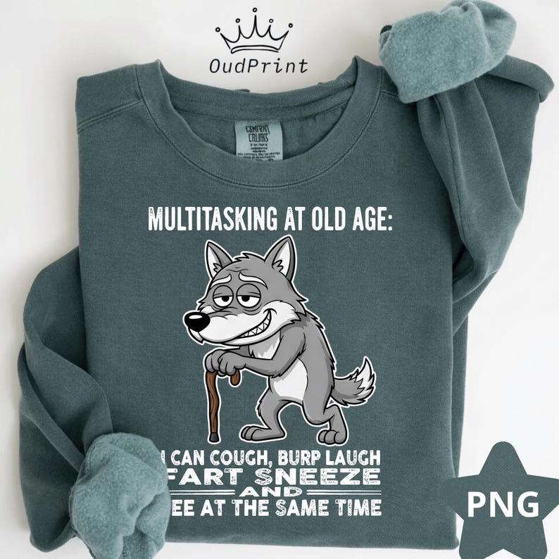 Pu&ograve; includere: Una felpa color verde acqua con la scritta "MULTITASKING AT OLD AGE:" e un lupo dei cartoni animati con un bastone. Il lupo sorride e il testo sottostante recita "I CAN COUGH, BURP LAUGH FART SNEEZE AND PEE AT THE SAME TIME."