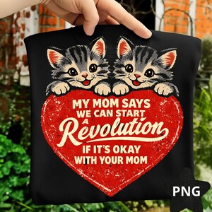 May include: Black t-shirt with a graphic of two cartoon kittens with grey and black stripes, above a distressed red heart. The heart has the text "MY MOM SAYS WE CAN START A Revolution IF IT'S OKAY WITH YOUR MOM."