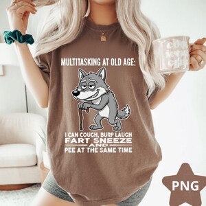 Pu&ograve; includere: T-shirt marrone con la scritta "MULTITASKING AT OLD AGE: I CAN COUGH, BURP LAUGH FART SNEEZE AND PEE AT THE SAME TIME." Presenta un lupo dei cartoni animati con un bastone. La maglietta &egrave; di vestibilit&agrave; ampia.