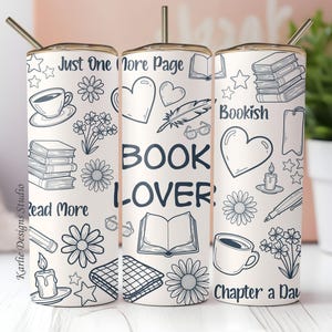 May include: A white tumbler with a gold lid and straw, decorated with black line art of books, flowers, hearts, and the words "Book Lover," "Just One More Page," "Read More," and "Chapter a Day."