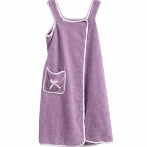 May include: A lavender wrap-around towel with white trim and a pocket featuring a white bow. The towel has a square neckline and shoulder straps. This spa-style towel is made of soft material.