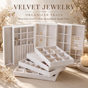 Może przedstawiać: Białe aksamitne tace organizera biżuterii z różnymi przegródkami i szczelinami. Tace są ułożone w stos i ułożone tak, aby eksponować naszyjniki, pierścionki i bransoletki. Tekst "VELVET JEWELRY ORGANIZER TRAYS" znajduje się na górze.